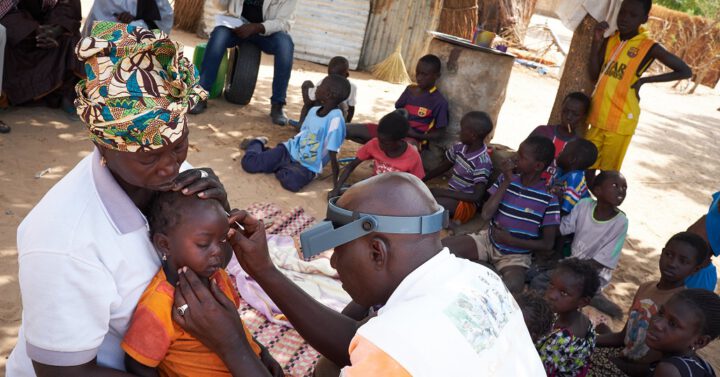 Optiker untersucht kleines Kind auf Trachome (Senegal)
