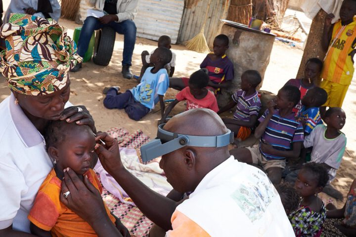 Optiker untersucht kleines Kind auf Trachome (Senegal)