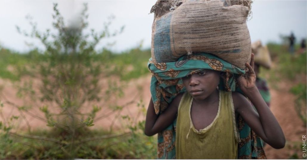 Junges Kind trägt schwere Last auf dem Kopf.